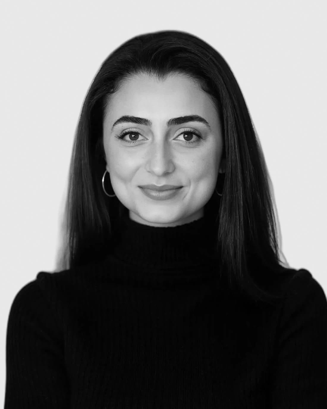 Professional headshot of a woman with long dark hair wearing a black turtleneck.