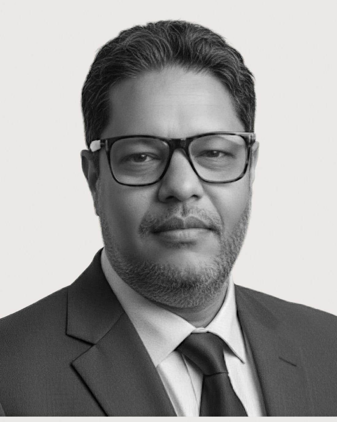 Black-and-white headshot of a bespectacled man in a suit and tie.